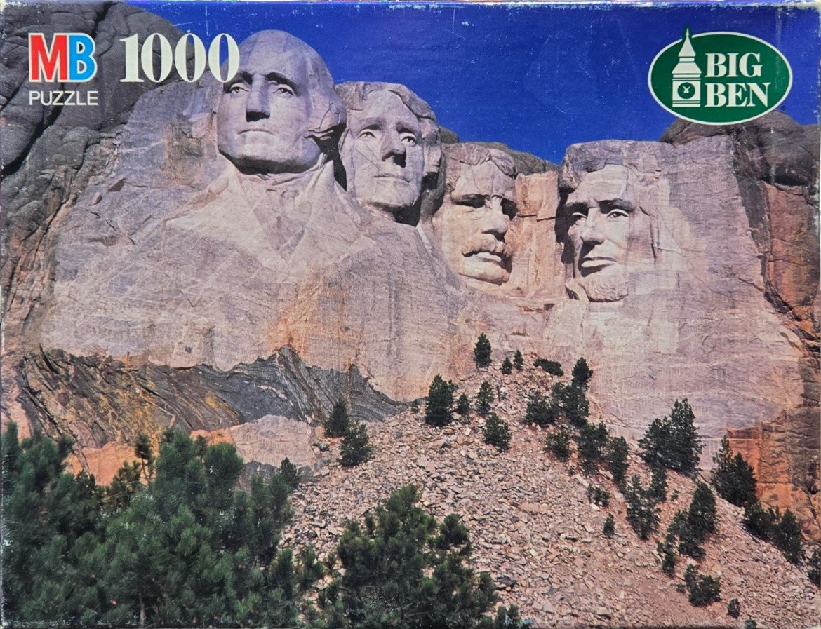 Mount Rushmore National Memorial with carved granite faces of four US presidents against a clear blue sky.