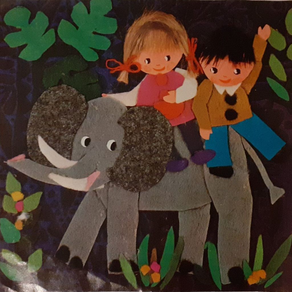 A girl and a boy ride on the back of a friendly elephant in a stylized, cut-paper jungle scene.