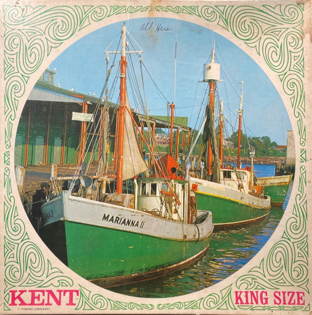 Two green and white fishing boats docked at a pier, framed by a decorative green border.