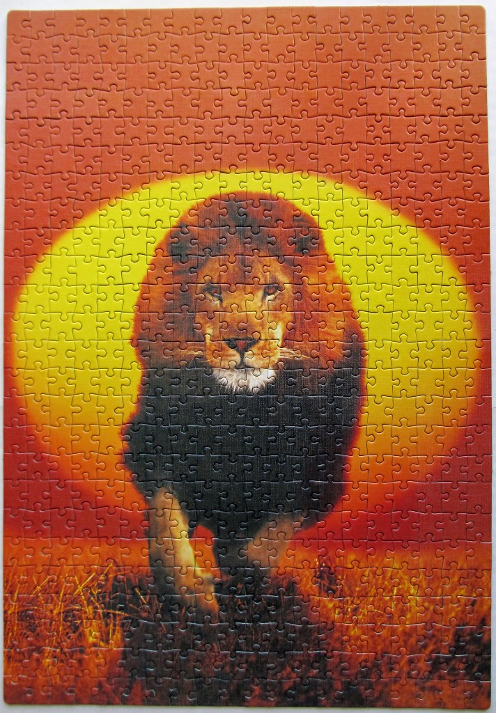 A male lion walking forward centered against a large, glowing yellow sun setting over an orange landscape.