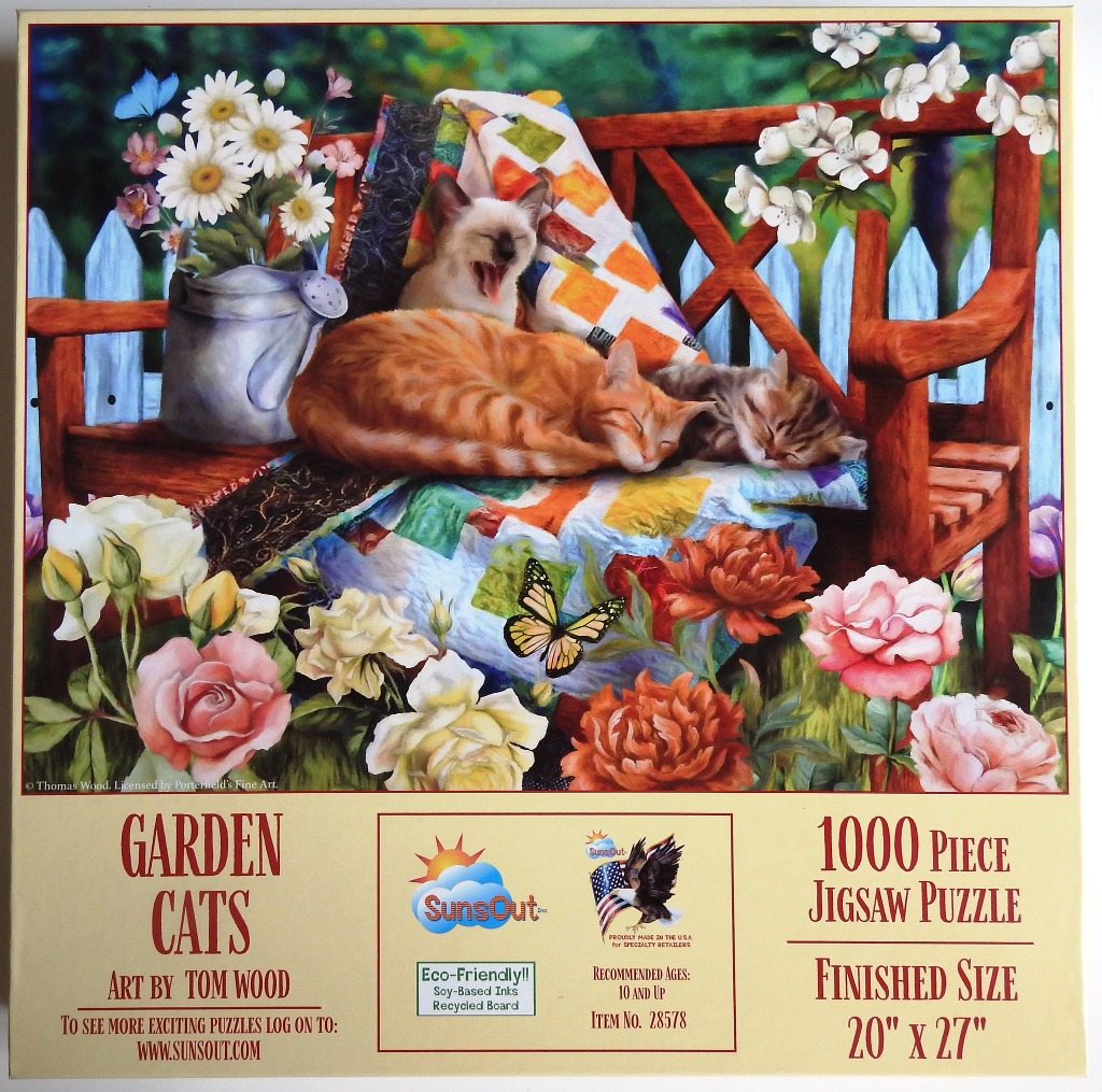Three cats sleeping on a wooden garden bench amidst flowers and a patchwork quilt