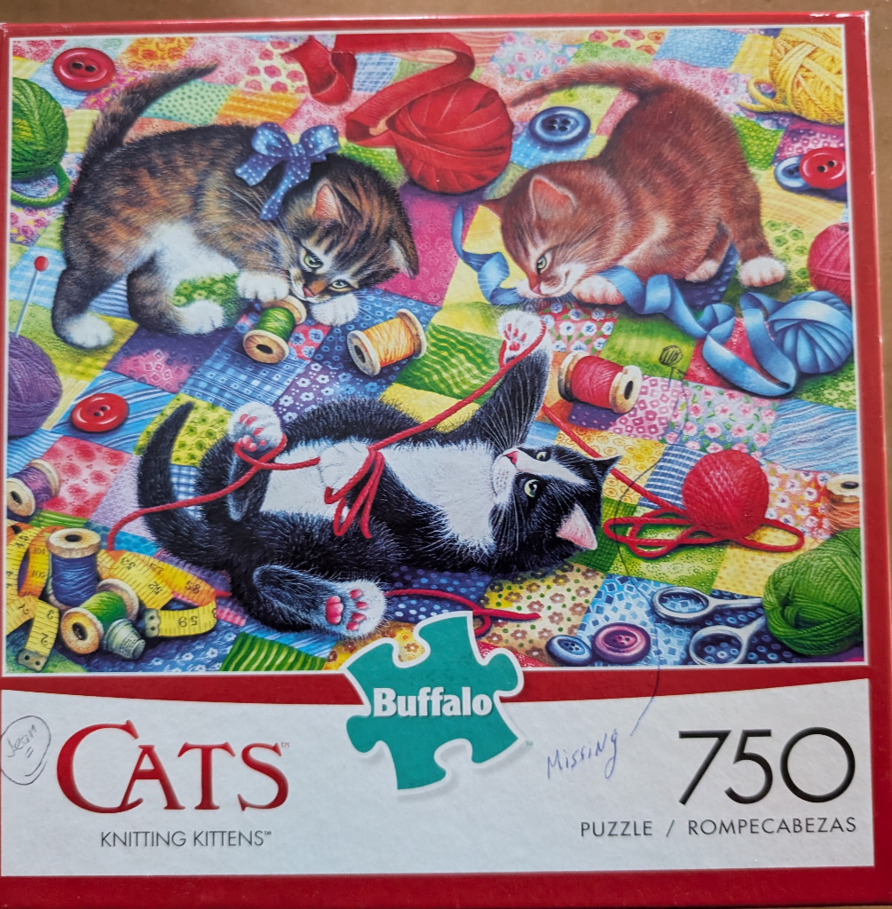 Three kittens playing with knitting supplies on a patchwork quilt