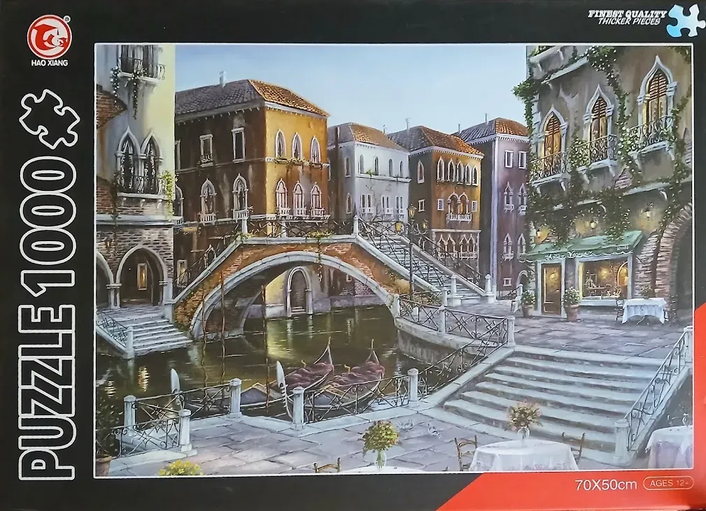An idyllic painting of a Venetian canal scene with stone buildings, a curved bridge, and parked gondolas.