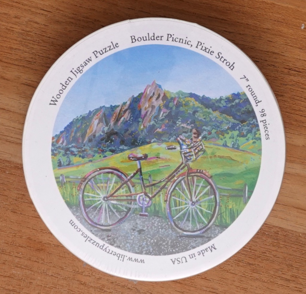 An impressionistic painting of a bicycle parked on a gravel path with the Flatiron rock formations in the background.
