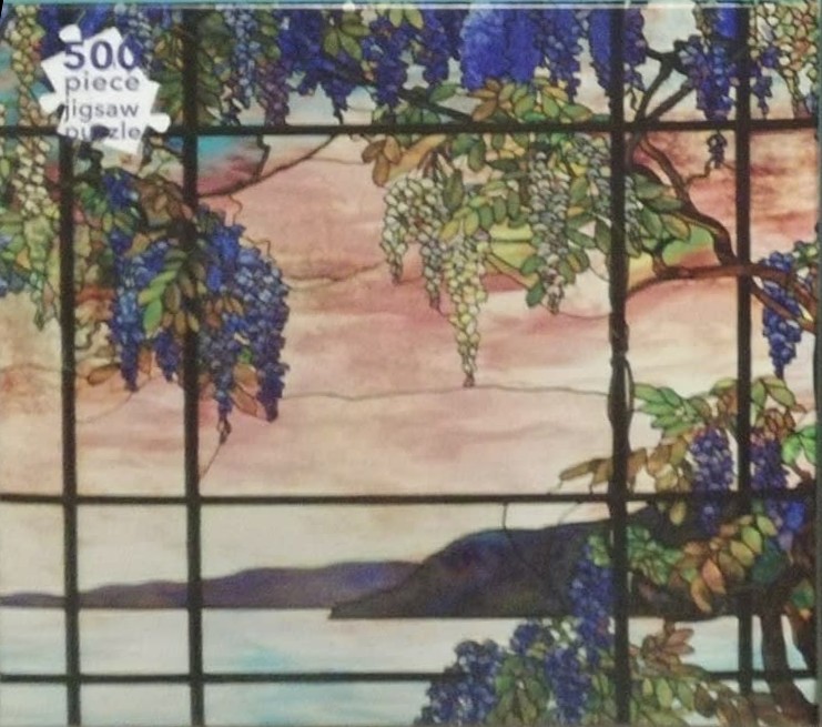 Stained glass artwork featuring hanging purple wisteria flowers against a coastal sunset view.