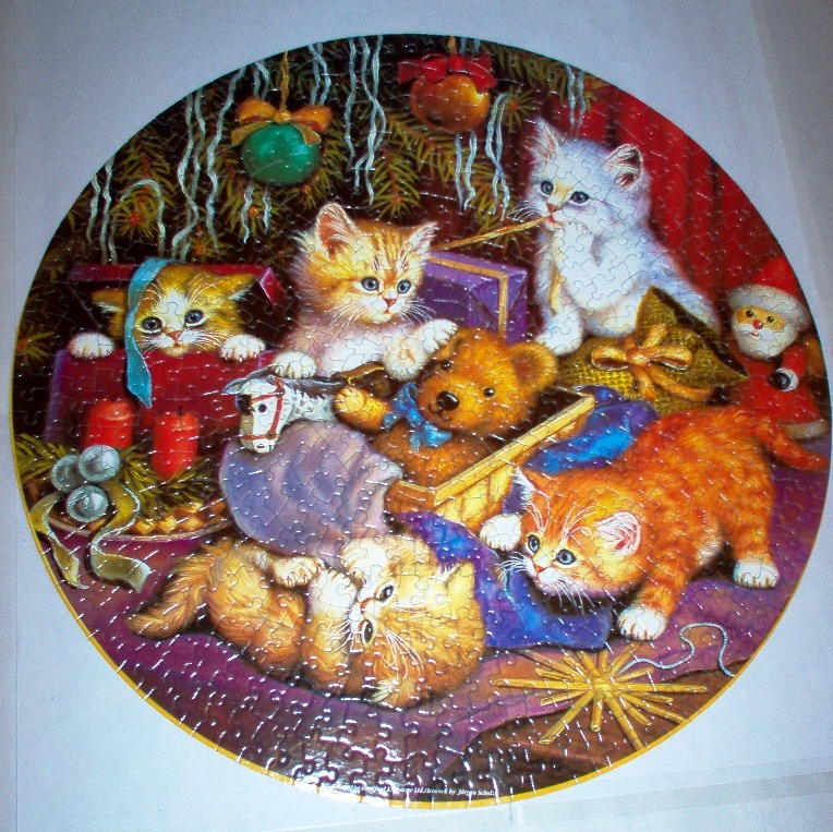 A circular illustration featuring several kittens and a teddy bear surrounded by Christmas decorations and gifts.
