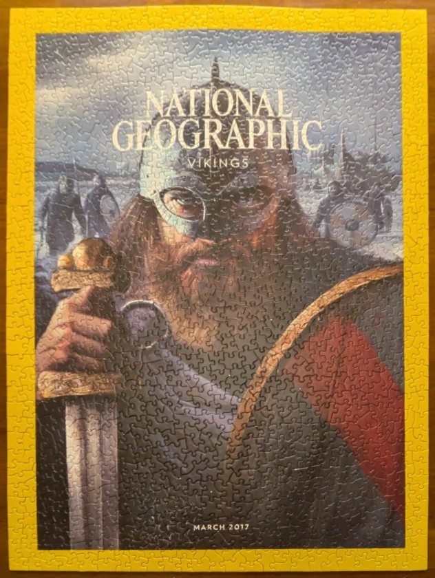 An illustration of a stern Viking warrior holding a sword, featured on a magazine cover.