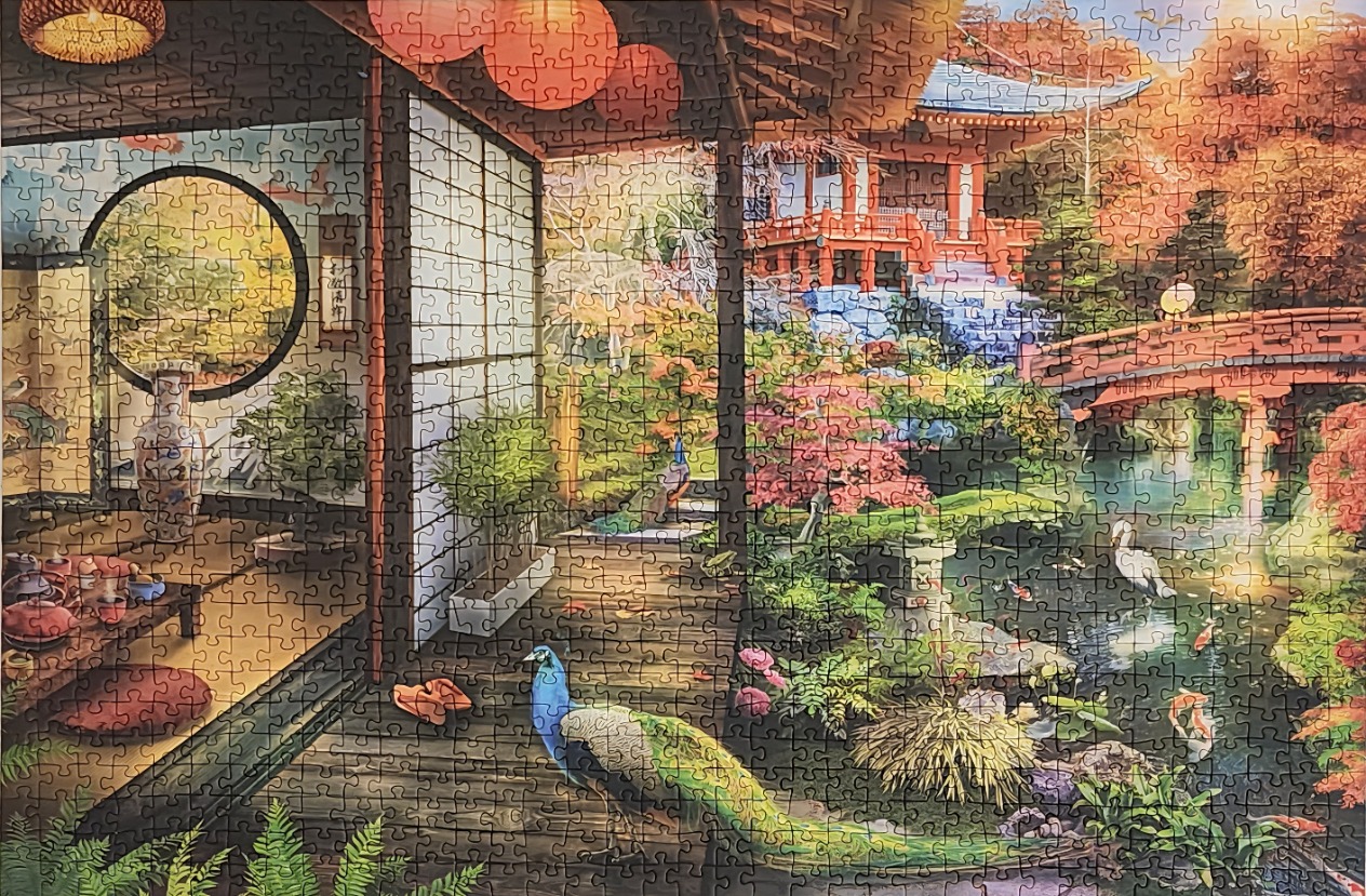 View from a traditional Japanese porch overlooking a lush garden with a red bridge, pond, and a peacock.