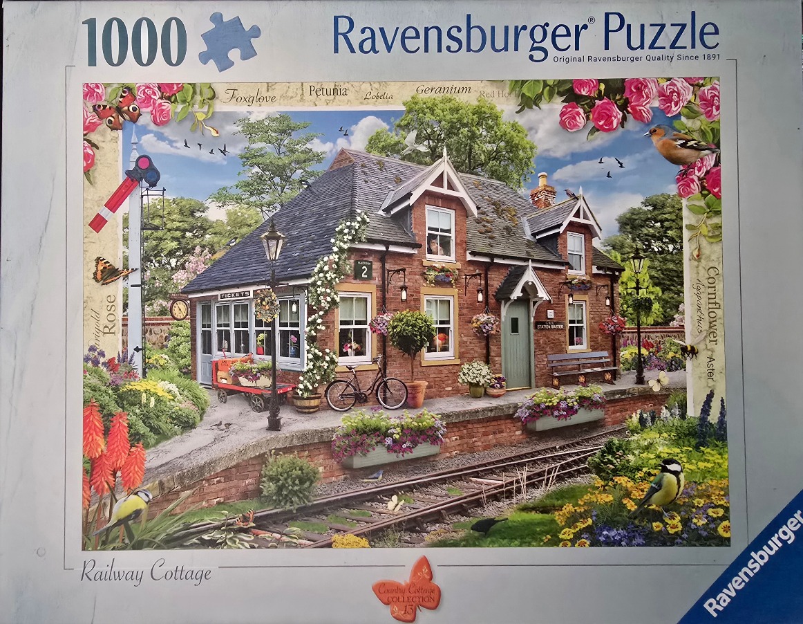 A charming brick railway cottage surrounded by vibrant flowers, a bicycle, and train tracks.