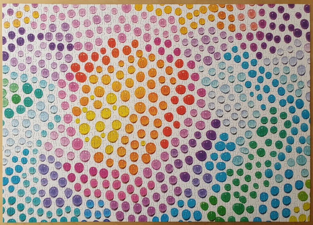 Abstract art of circular drops in a spectrum of colors on a white background.