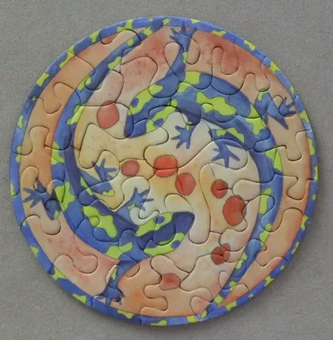 Circular illustration of stylized blue and lime green lizards spiraling around a central orange-spotted core.