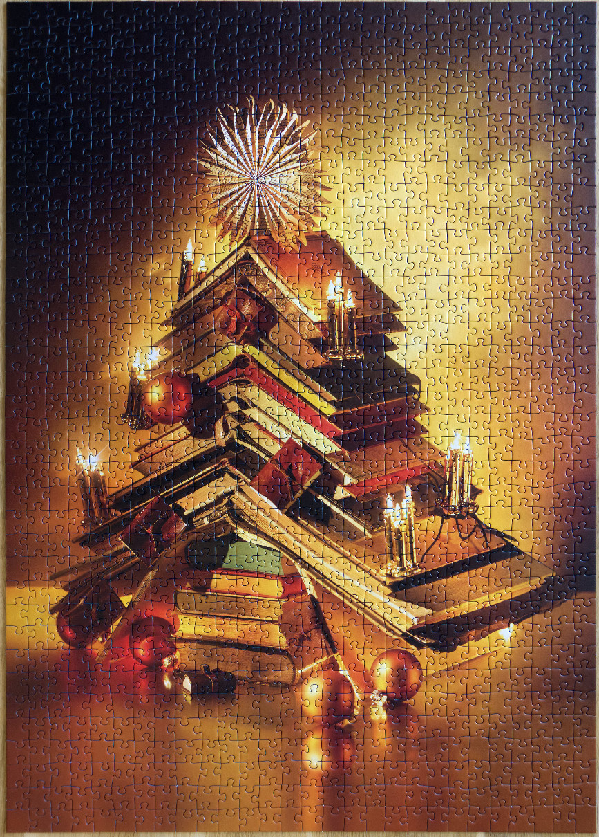 A Christmas tree shaped stack of vintage books decorated with candles and ornaments against a golden background.
