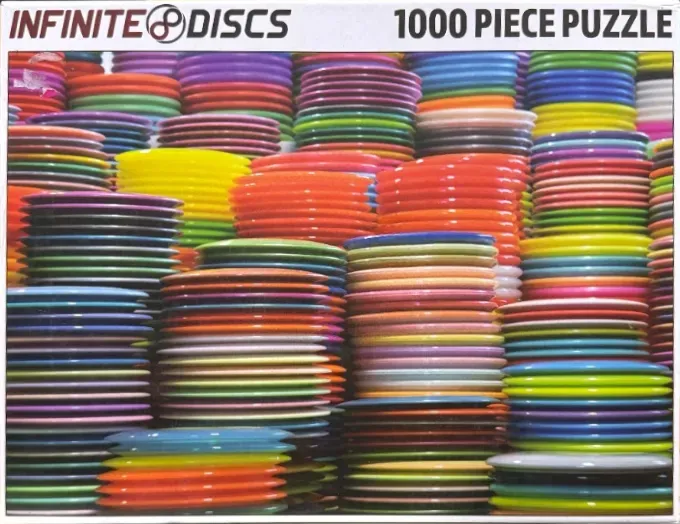 A dense, colorful wall of numerous stacked disc golf discs of various bright shades.