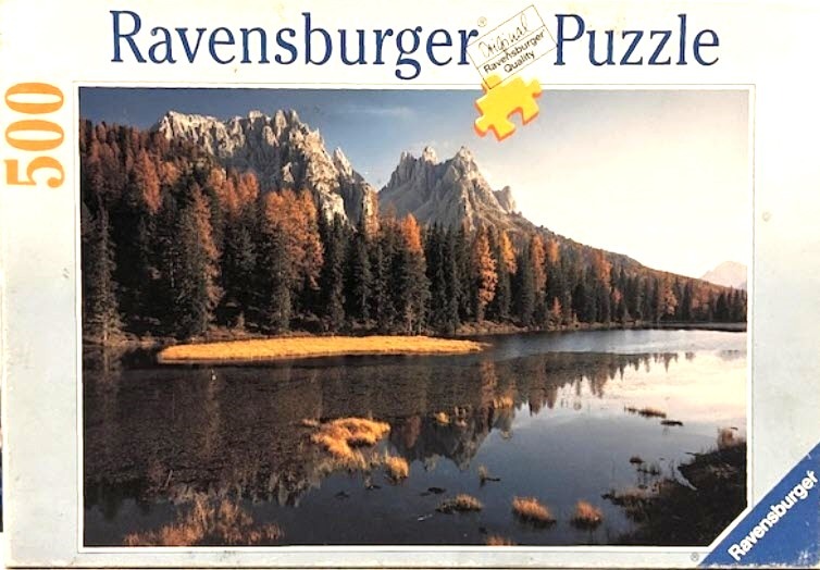 A scenic photograph of a tranquil mountain lake reflecting craggy peaks and autumn forest foliage.