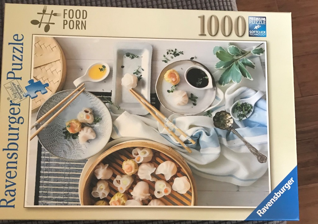 A top-down photographic composition of various dim sum dishes, sauces, and chopsticks arranged on a light tabletop.