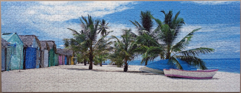 A scenic panoramic view of a tropical beach with colorful huts, palm trees, and two boats on the sand.