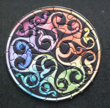 A circular illustration featuring stylized, colorful, swirling organic shapes against a black background.