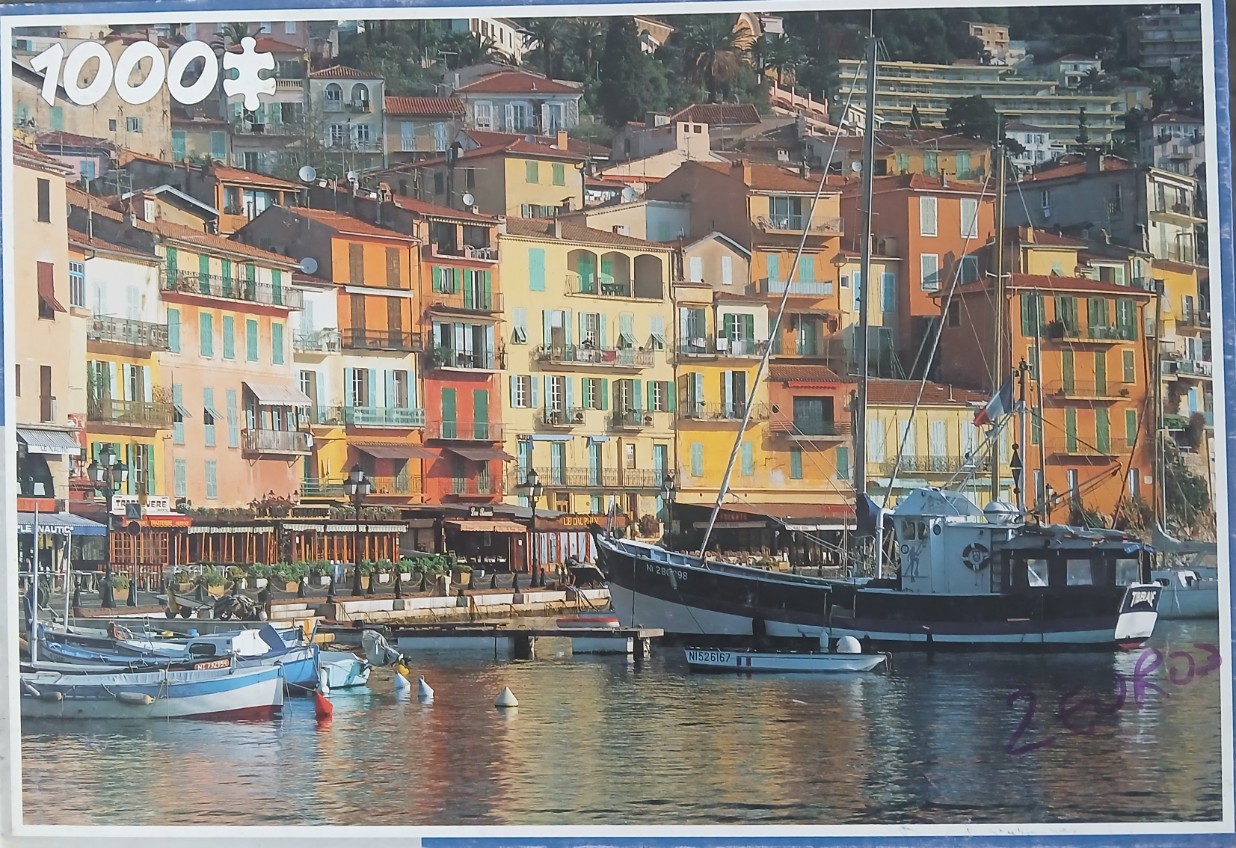 A Mediterranean harbor scene with colorful buildings and fishing boats on the water.