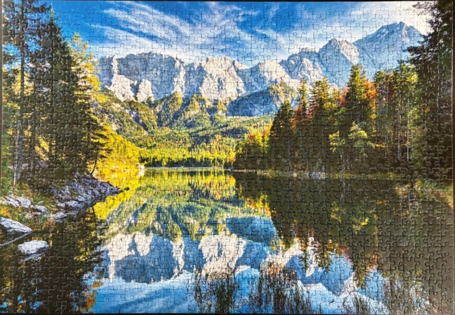 Mountain range reflecting in a serene lake surrounded by autumn-toned forest