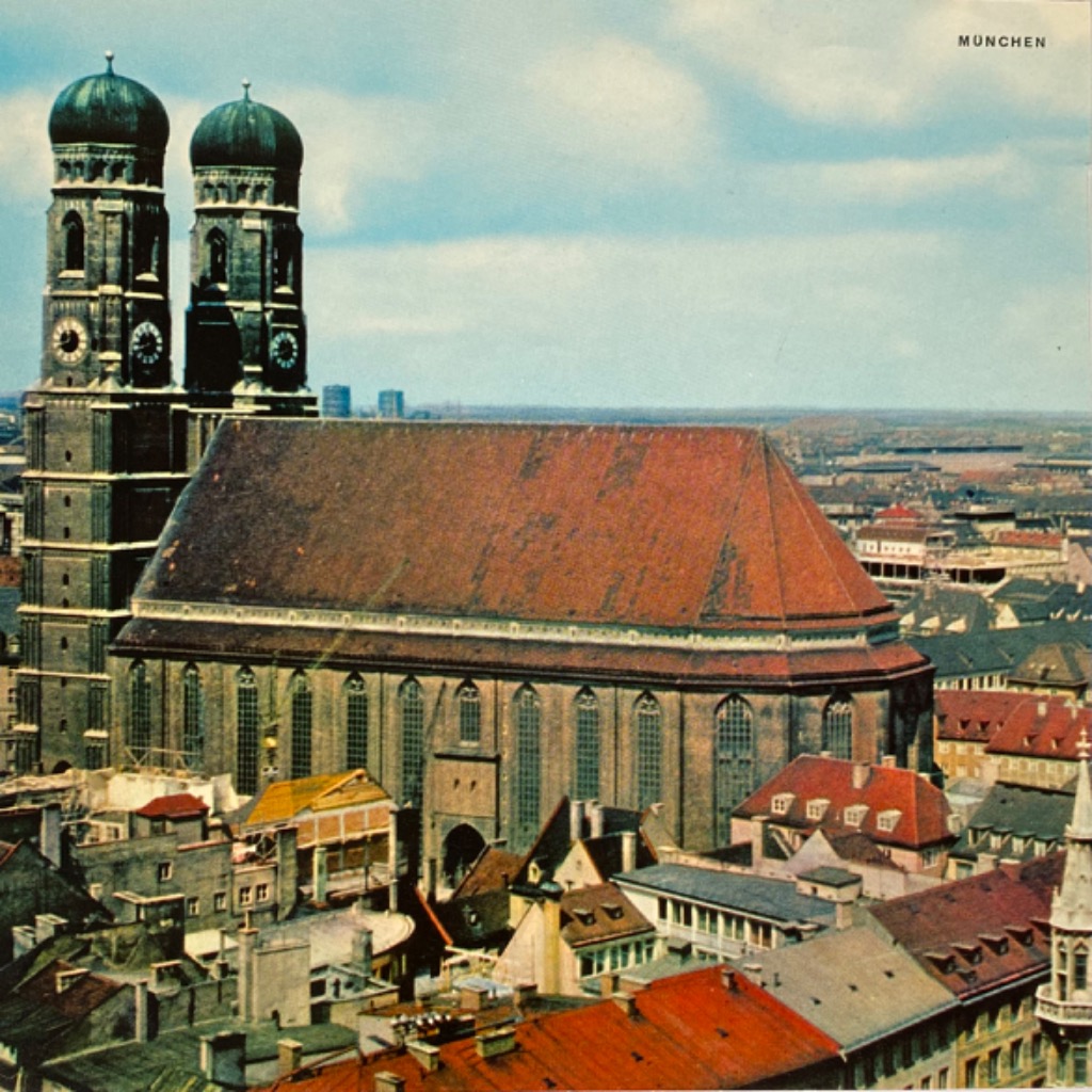 High-angle view of the Munich Frauenkirche in Germany with a city skyline in the background.