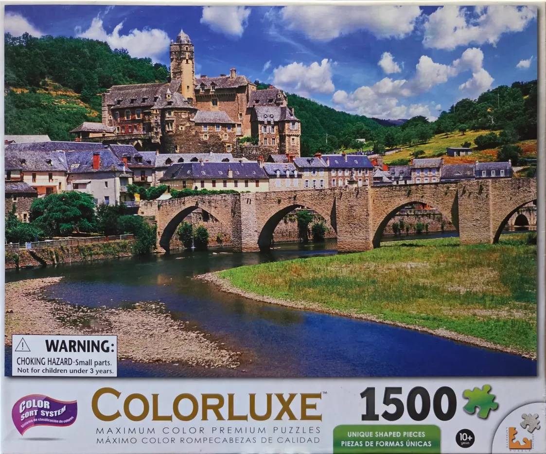 A scenic landscape featuring a medieval stone castle overlooking a village and a multi-arched bridge over a river.