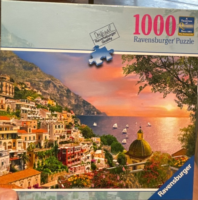 Coastal Italian village of Positano at sunset with colorful buildings, a domed church, and sailing boats on the sea.