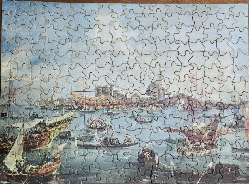 An oil painting of a busy Venetian harbour with various boats and ships on a calm sea.