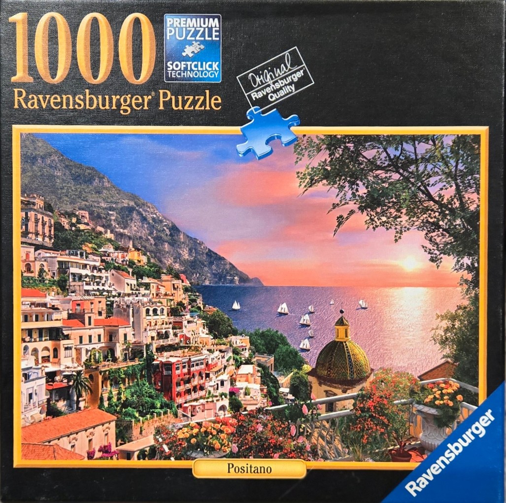 Scenic view of the Positano coastline in Italy at sunset featuring colorful hillside architecture and sailboats.