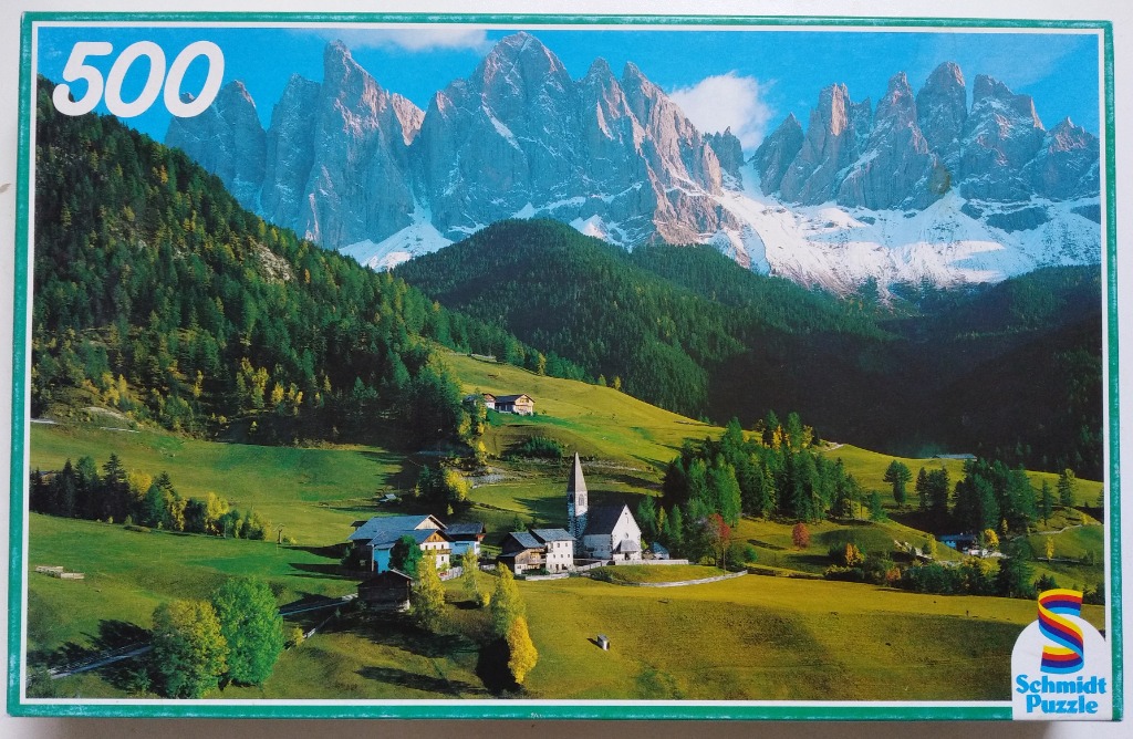 A scenic photograph of the Santa Magdalena village in the Italian Dolomites with jagged peaks in the background.