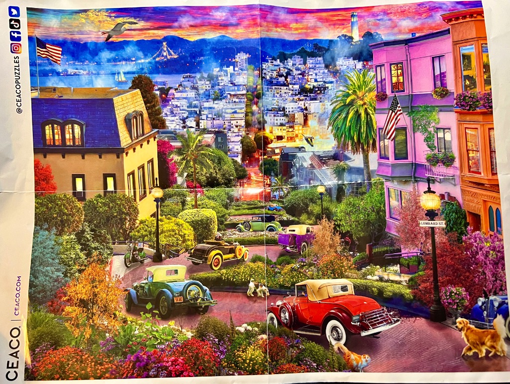 Vintage cars driving down a winding, flower-lined San Francisco street under a vibrant sunset sky.