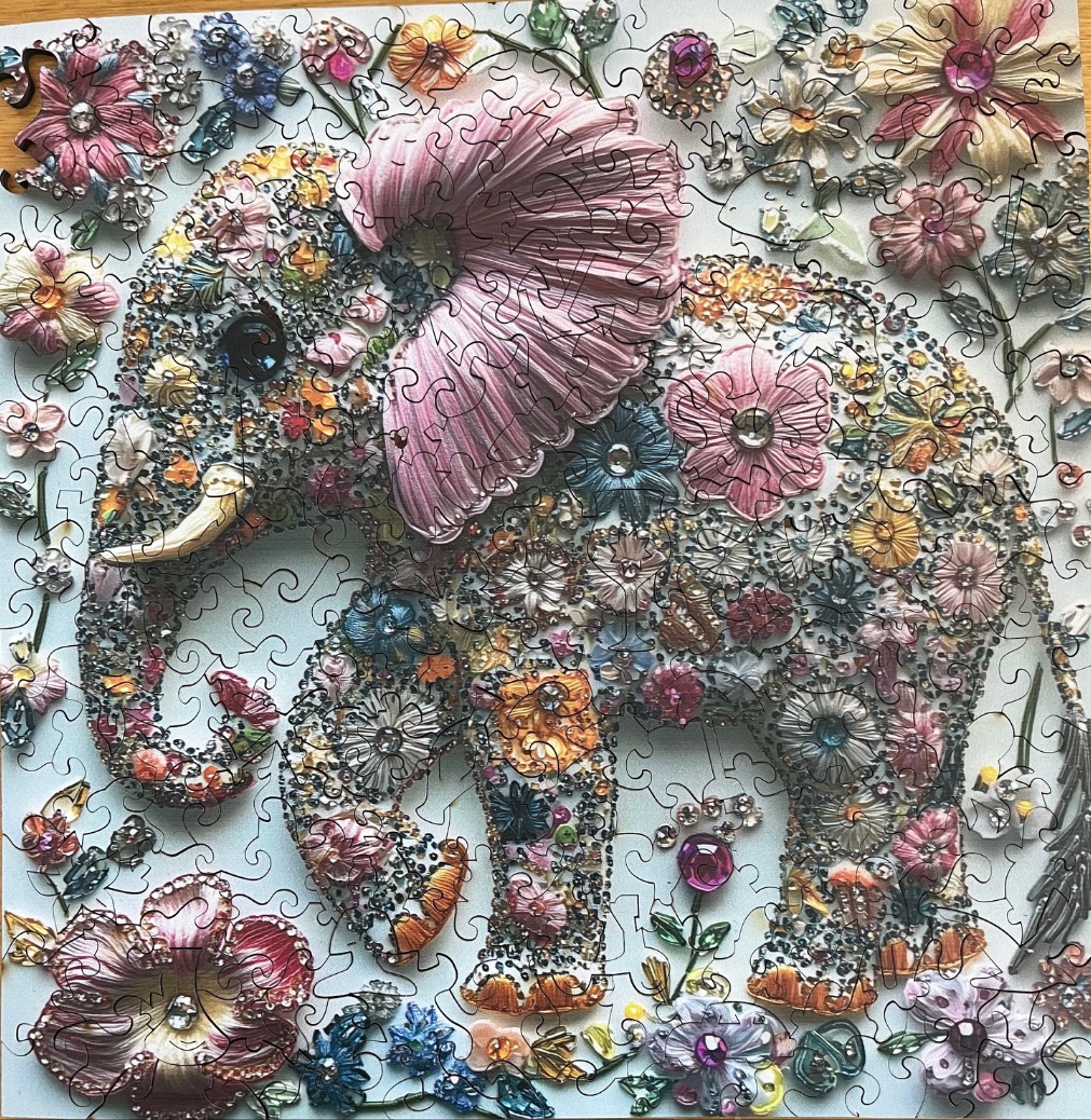 An elephant silhouette filled with colorful vintage floral brooches and jewelry against a pale blue background.