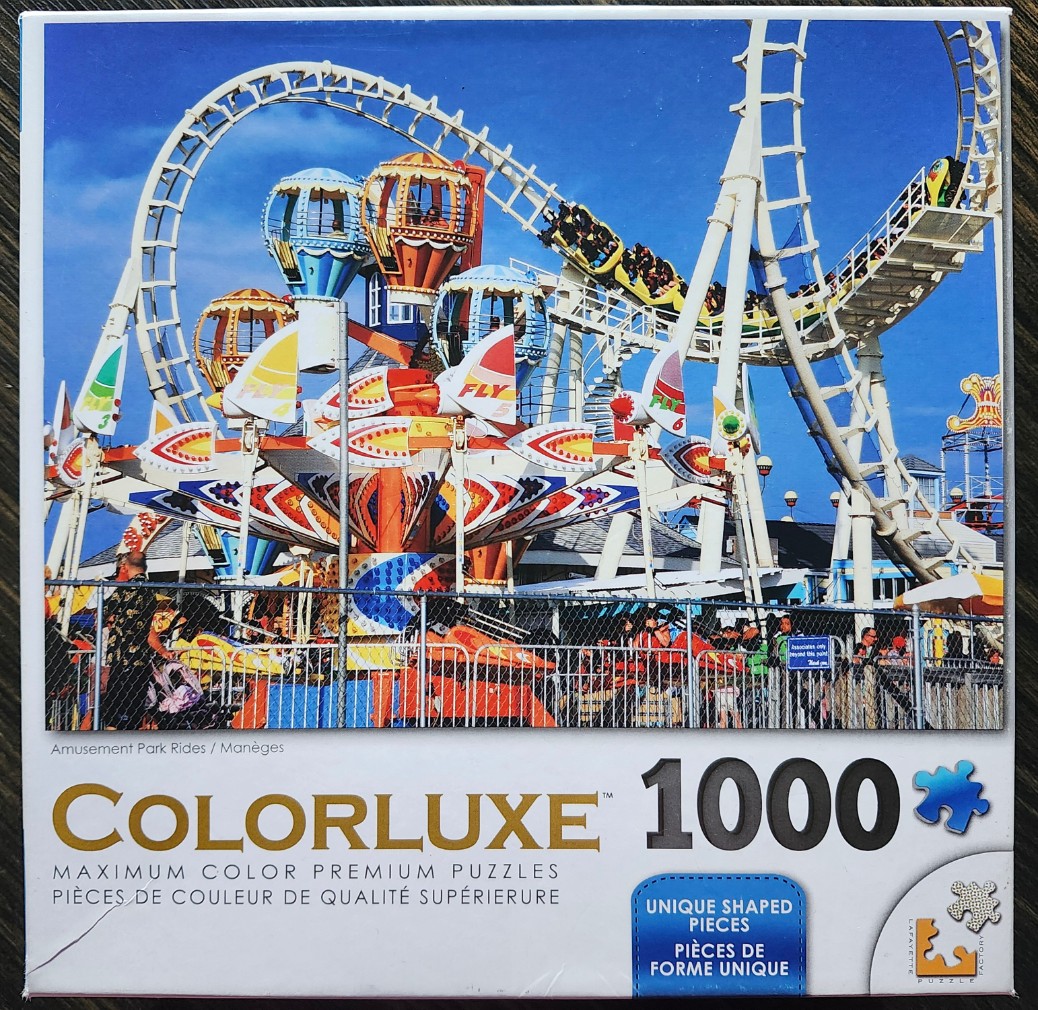 A roller coaster and a spinning amusement park ride against a clear blue sky.