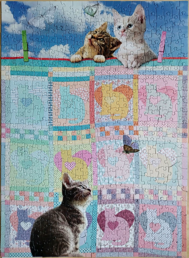 A collage featuring kittens, butterflies, and a pastel patchwork quilt with rabbit and cat motifs.