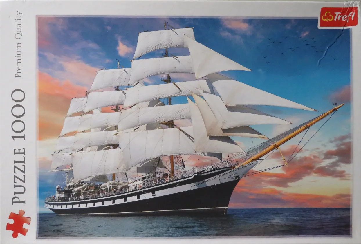 A majestic tall ship with white sails under a colorful sunset sky on the open ocean.