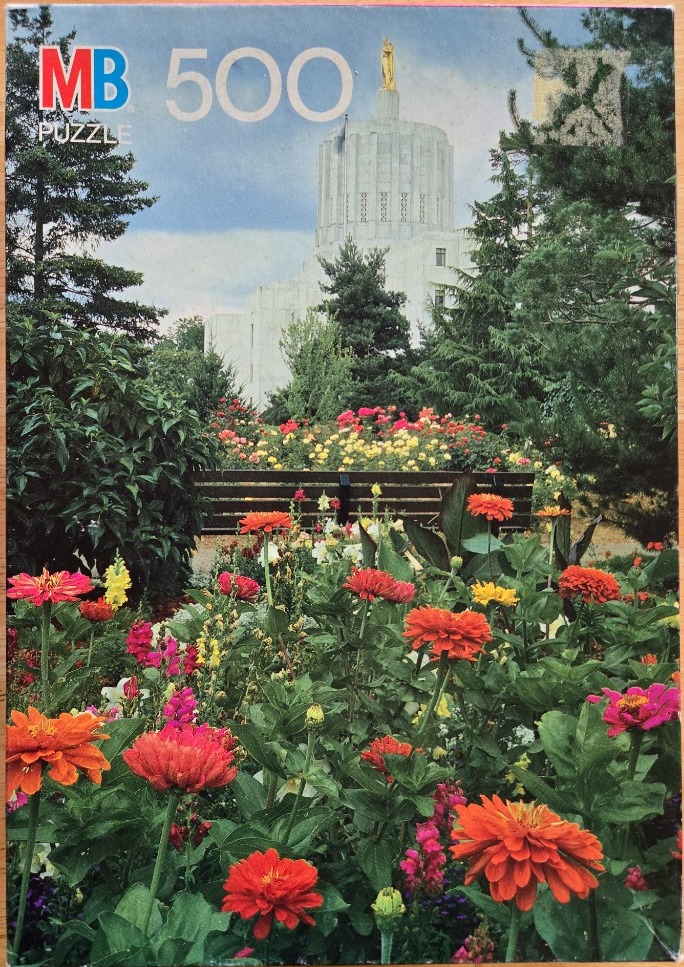 A lush garden of vibrant zinnias in the foreground with a neoclassical state capitol building in the background.