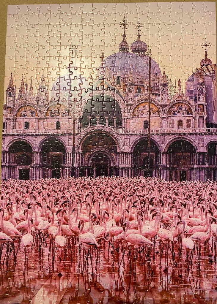 A flock of pink flamingos standing in water in front of St. Mark