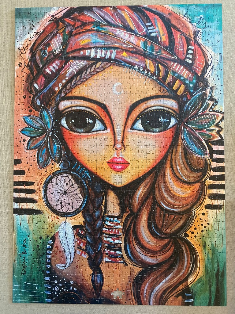 Stylized portrait of a young woman with a patterned headwrap, large expressive eyes, and a dreamcatcher earring.