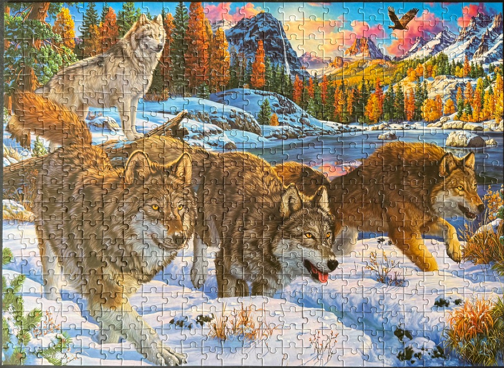 Four wolves in a snowy mountain landscape at sunset
