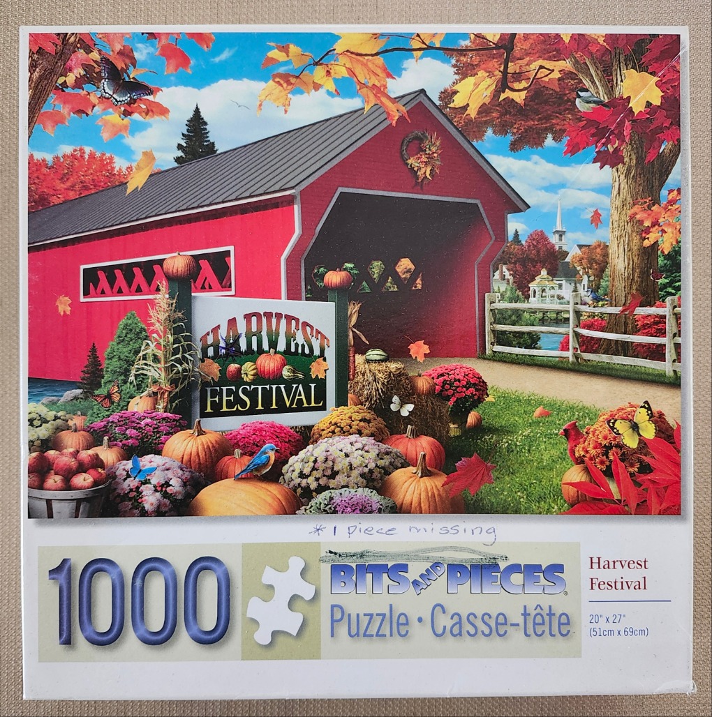 A red covered bridge surrounded by autumn foliage, pumpkins, and flowers with a Harvest Festival sign in the foreground.