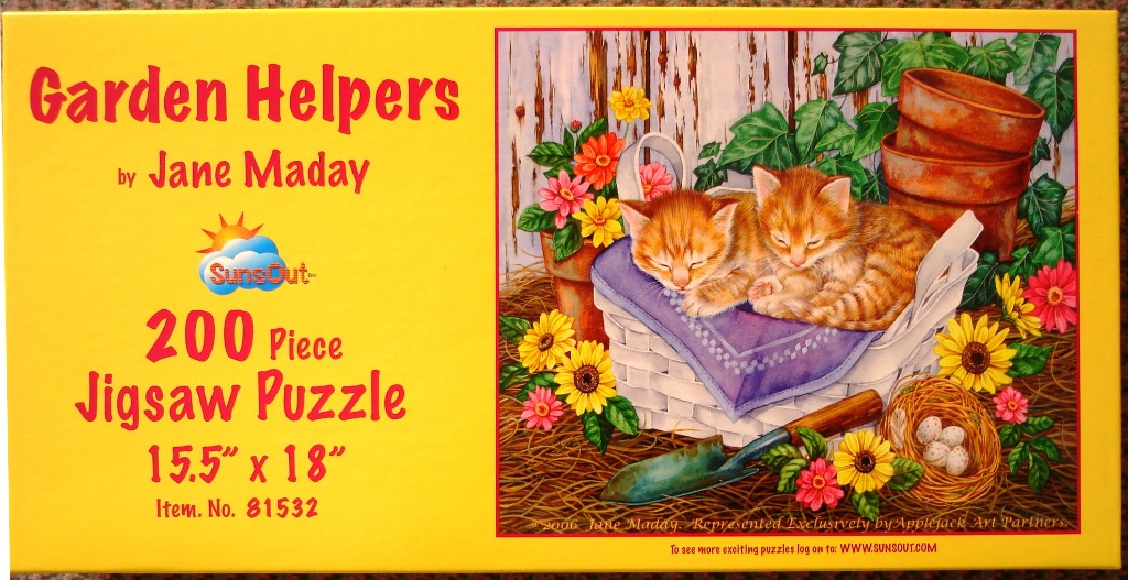Two ginger kittens sleeping in a white wicker basket in a garden setting surrounded by flowers.