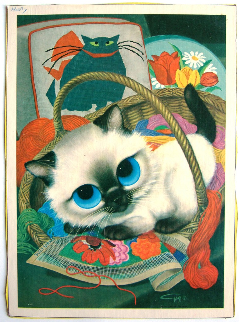An illustration of a wide-eyed Siamese kitten sitting in a wicker basket filled with colorful yarn and needlepoint.