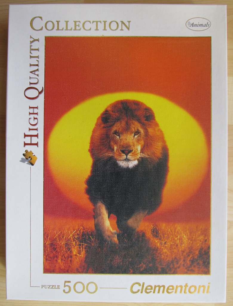 A male lion walking forward against a large, bright yellow sun set against an orange savanna sky.