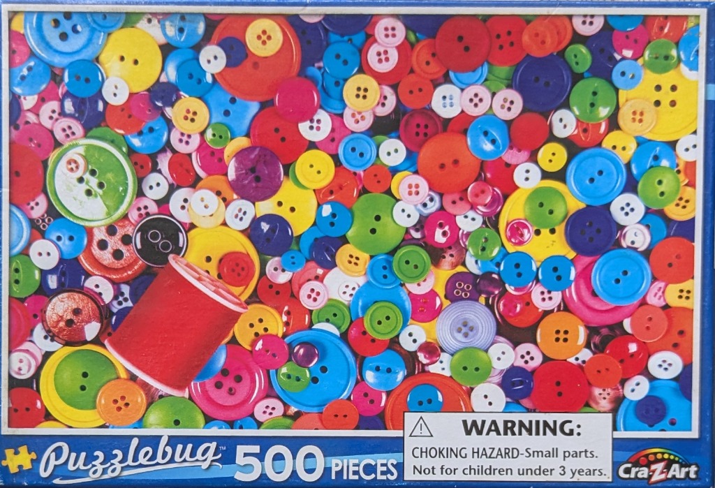 A dense, colorful collection of various sewing buttons in many sizes and colors with a red spool of thread.