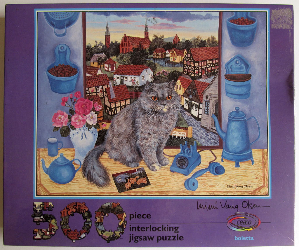 A long-haired grey cat sits on a wooden windowsill overlooking a village scene.