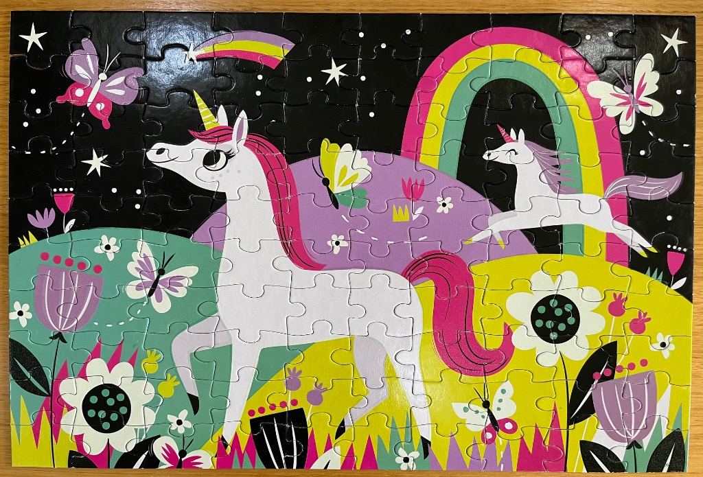 A whimsical cartoon scene featuring two unicorns in a vibrant, colorful garden under a starry black night sky.