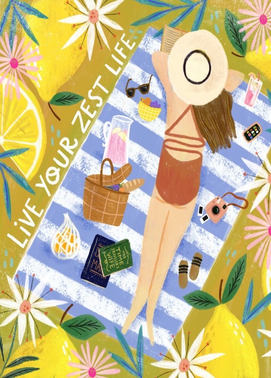 An overhead view of a woman relaxing on a blue-striped beach towel surrounded by lemons and flowers.