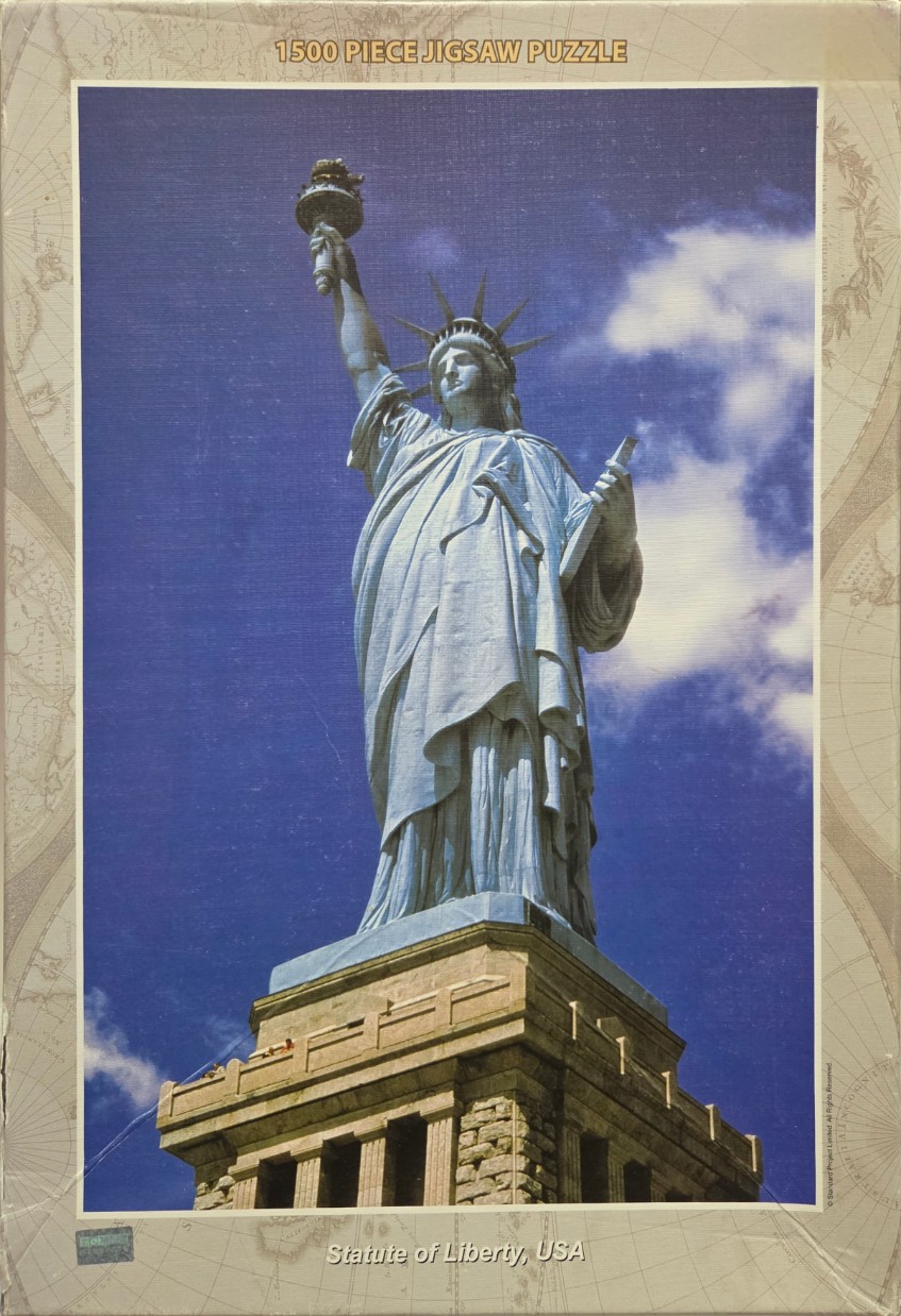The Statue of Liberty standing atop its stone pedestal against a bright blue sky.