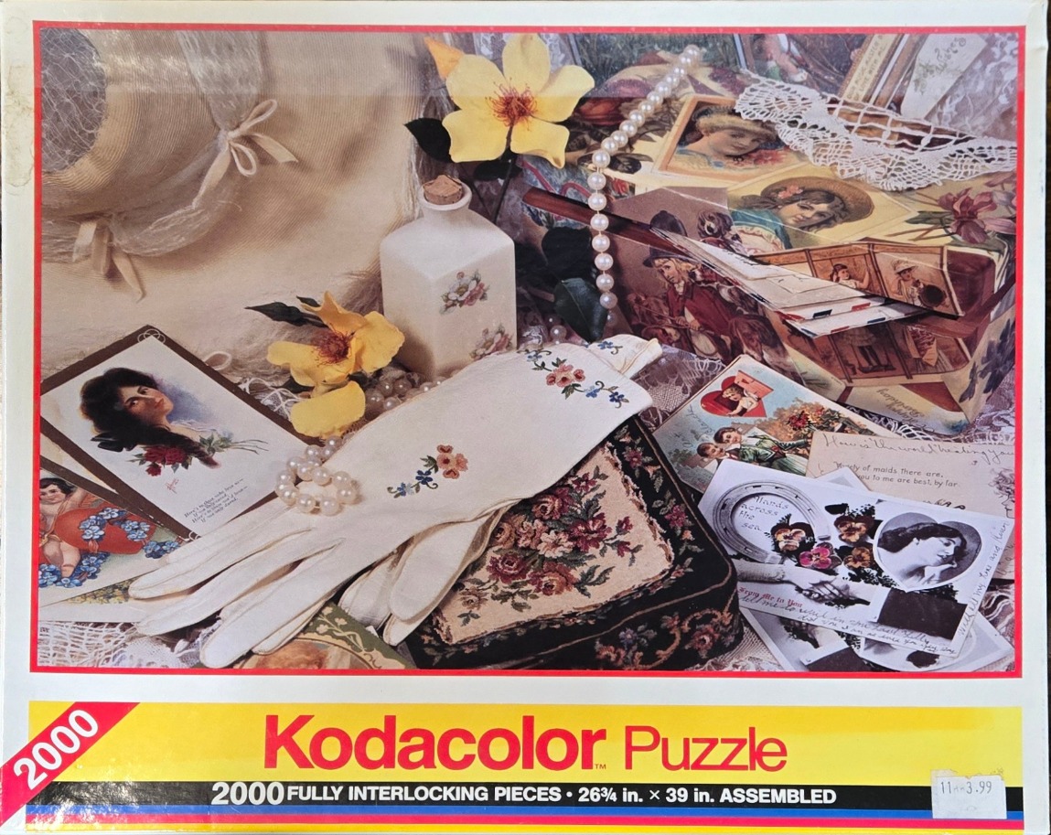A nostalgic still life arrangement of vintage postcards, pearls, a hat, and floral embroidery.