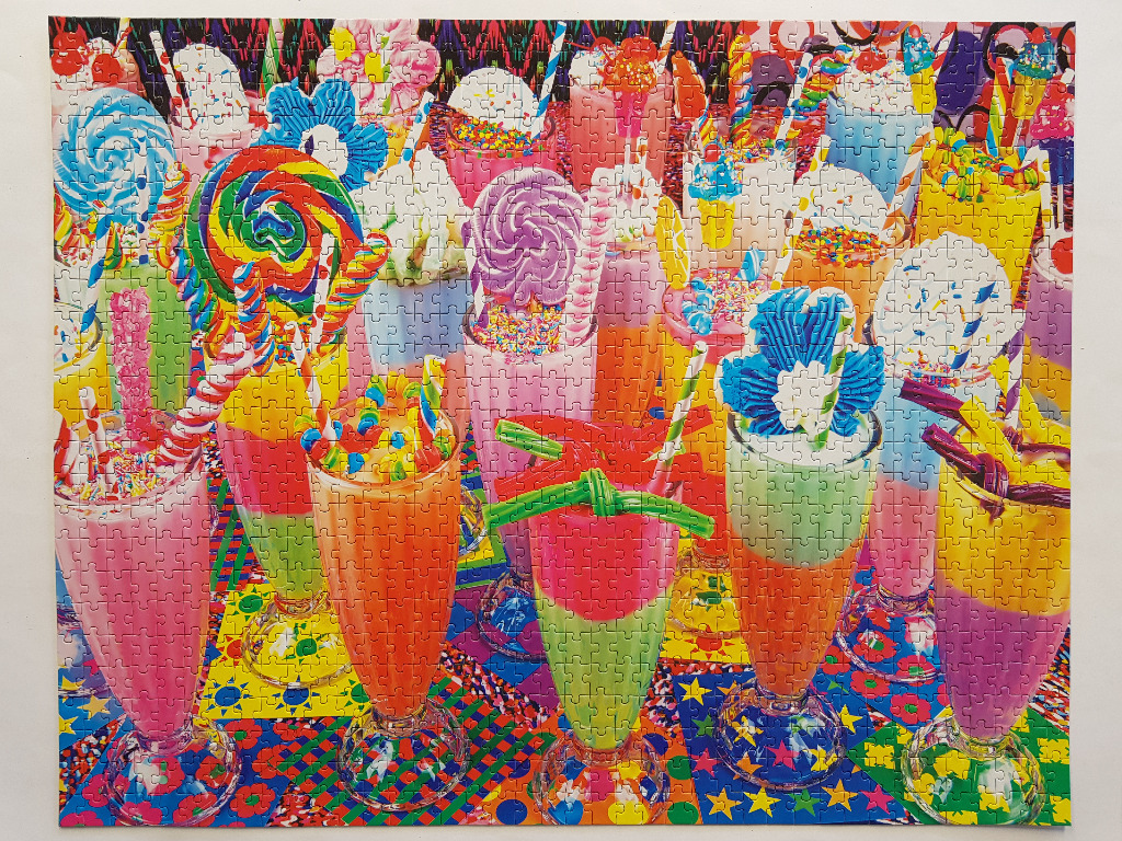 A collection of colorful, multi-layered milkshakes topped with vibrant candies and lollipops.