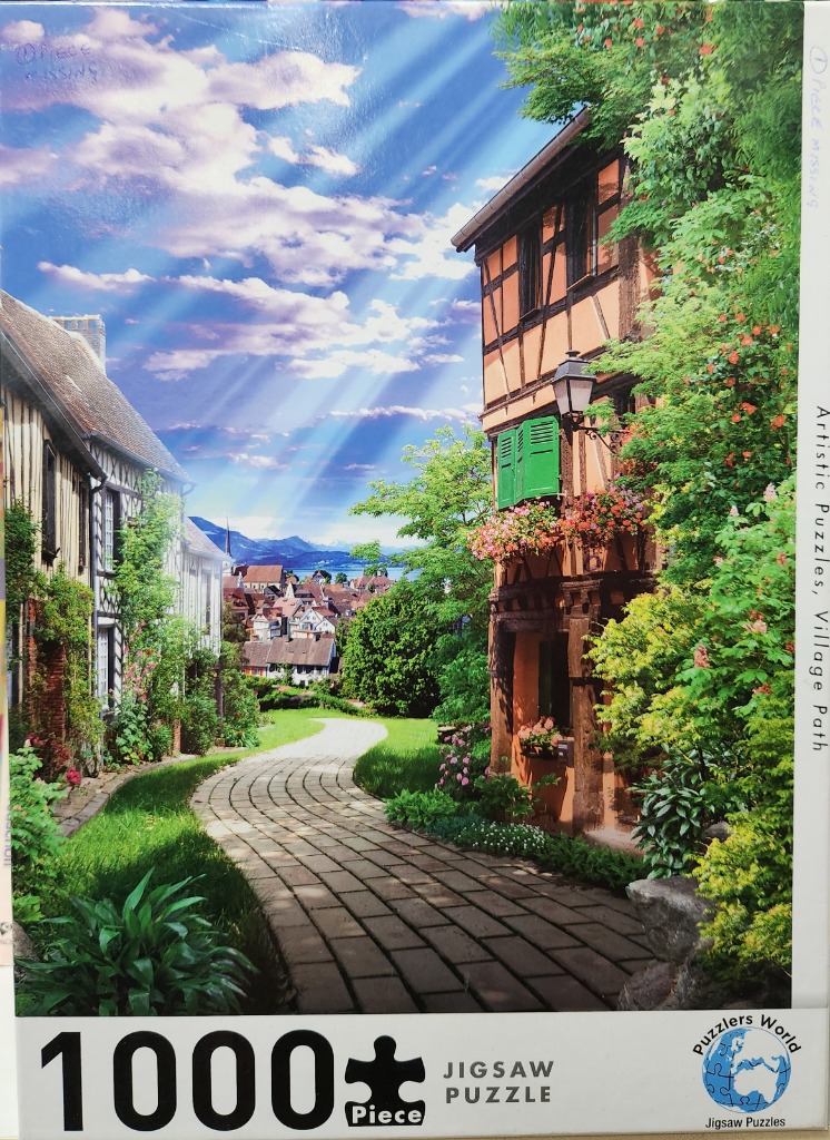 A European half-timbered village street with a stone path leading toward distant mountains under a dramatic sunlit sky.